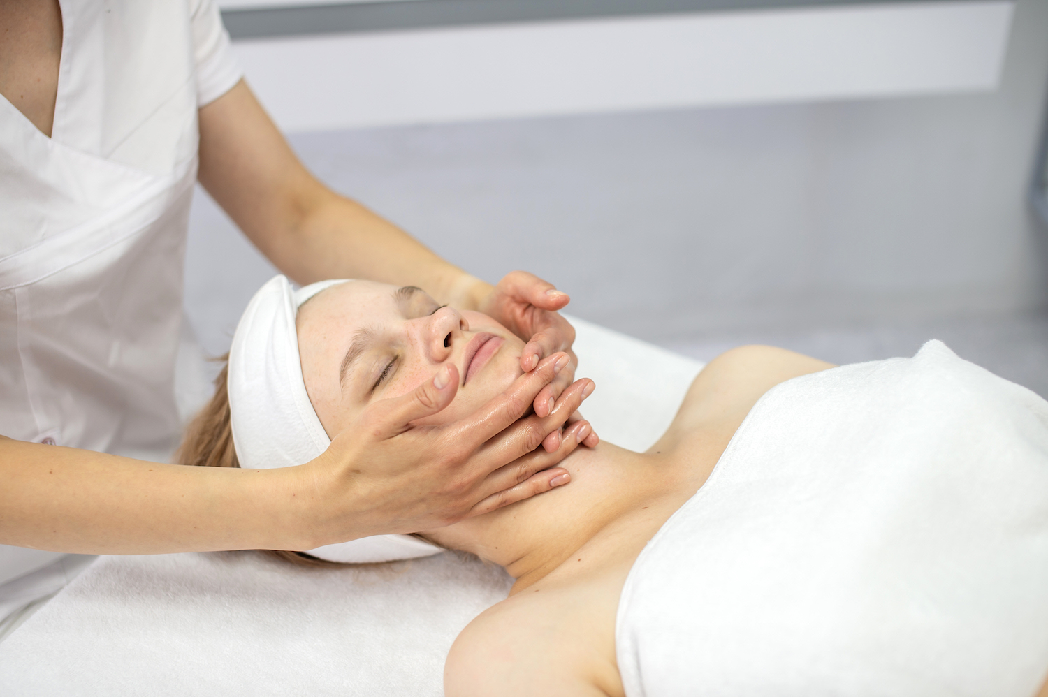 A female client closes her eyes and relaxes while receiving a facial