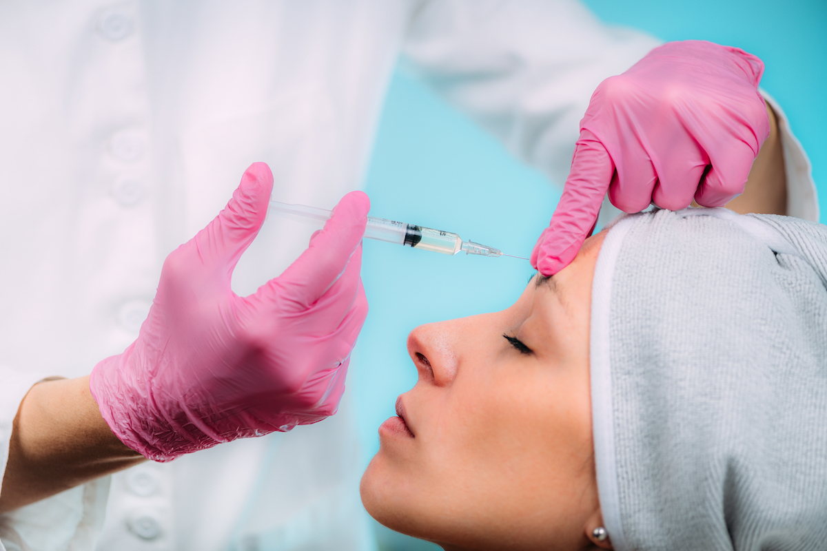 Close up of a medical provider positioning an injection into a female patient's forehead