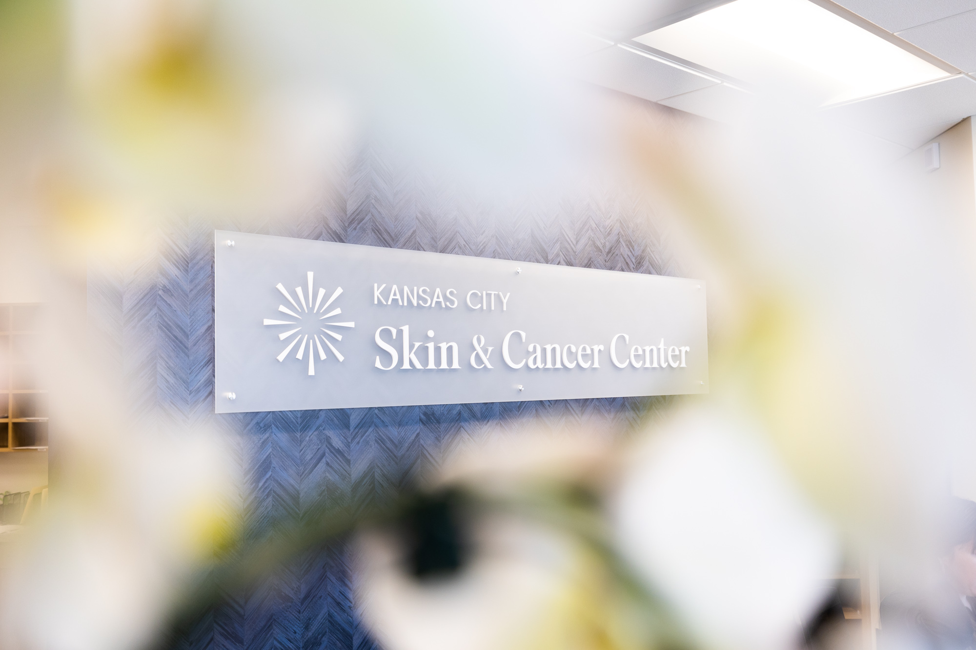 Most of the image is out of focus, but in the middle a sign that says Kansas City Skin and Cancer Center is clear.