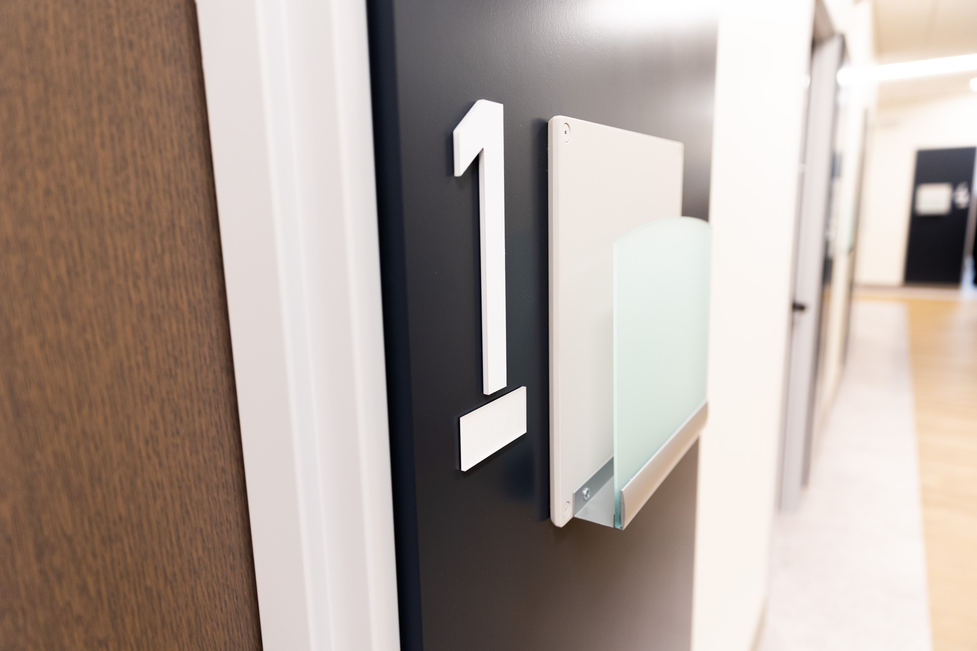 Sign outside of a door has the number one and then a spot for papers or folders.