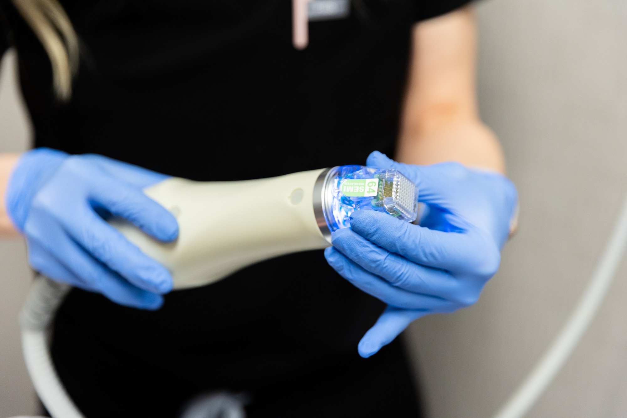 A close up of a Kansas City Skin and Cancer Center professional preparing the microneedling tool. She is wearing blue medical gloves.