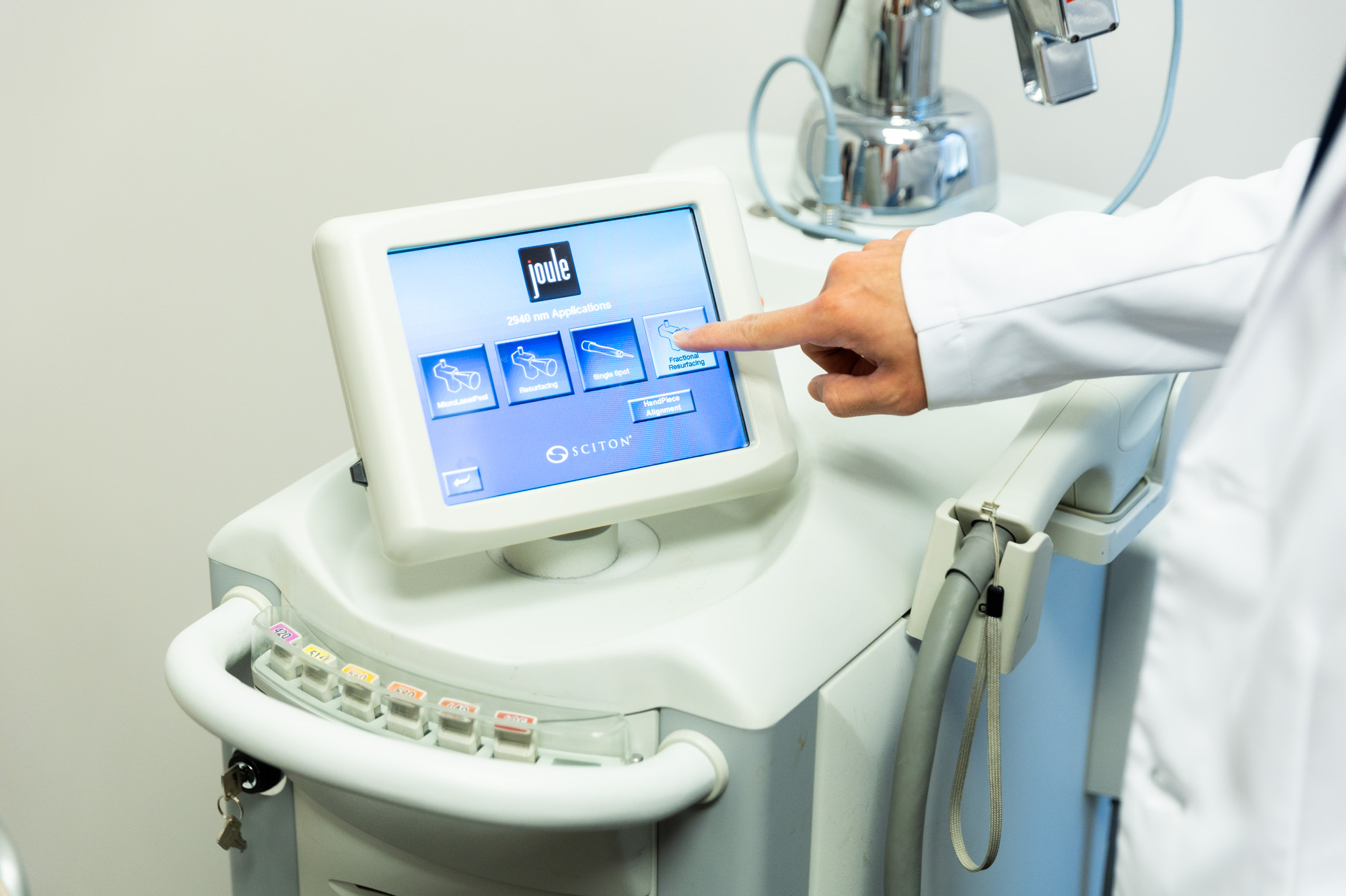 A doctor's hand points to a setting on a machine. The screen reads "joule" and has four different settings.