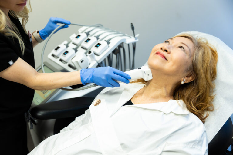 A female patient reclines back as she receives TruSculpt treatment.