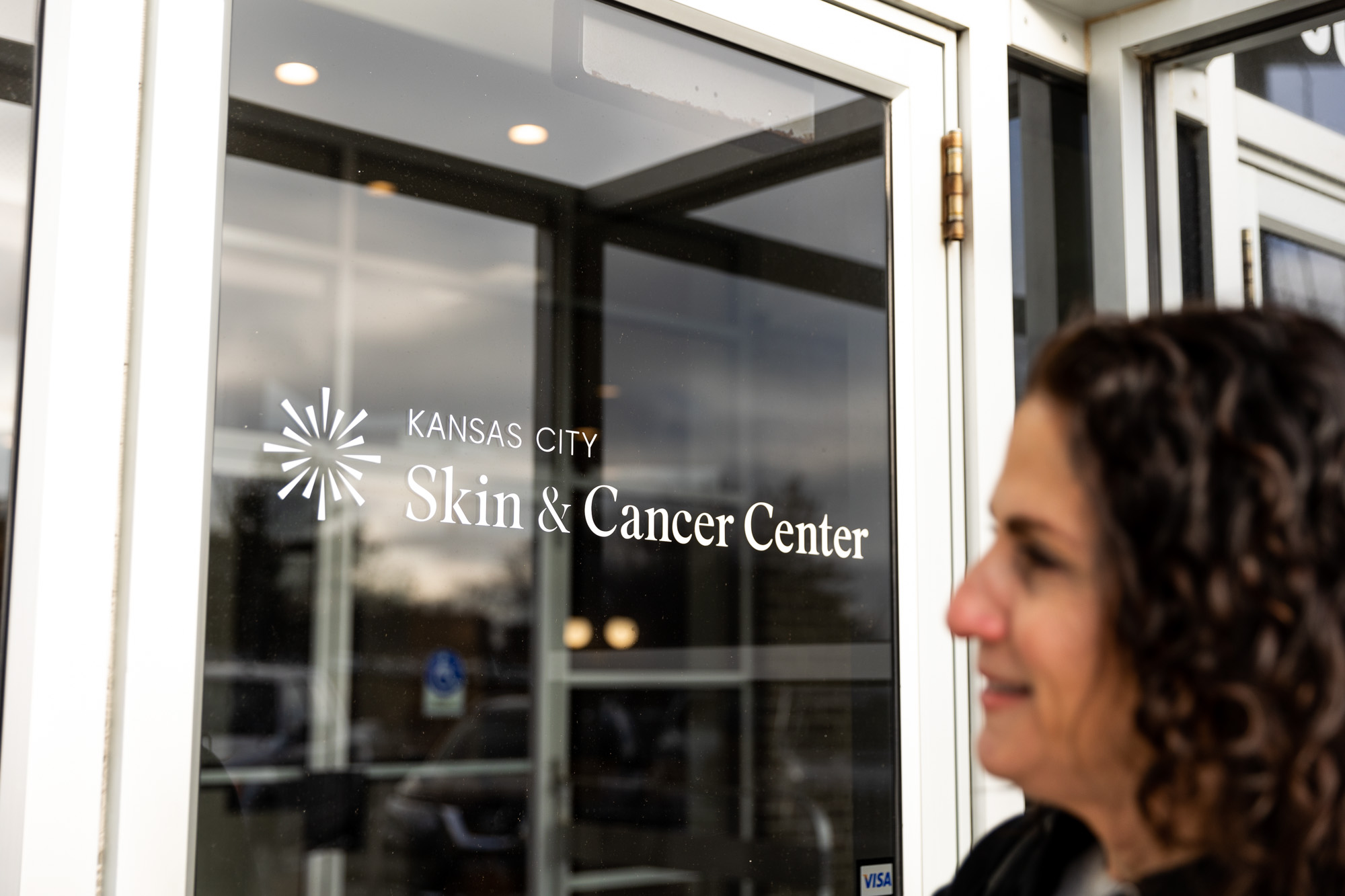 A Kansas City Skin and Cancer Center employee smiles and laughs while taking notes on a clipboard.