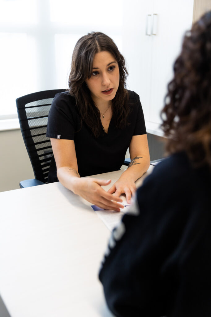 A Kansas City Skin and Cancer Center employee sits behind a desk and reviews different options with a client during a consultation.