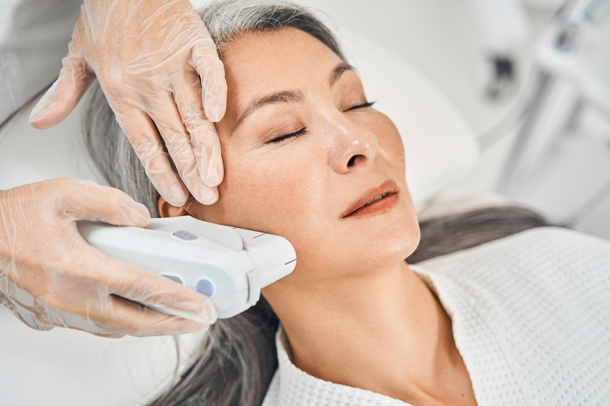 An older woman is lying down with her eyes closed for a session of intense pulsed light therapy in Kansas City.